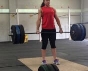 Woman holding a barbell at hip height in a gym